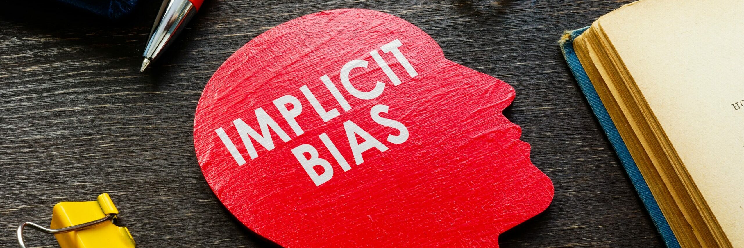 Cutout of a head with the word Implicit Bias on a work desk