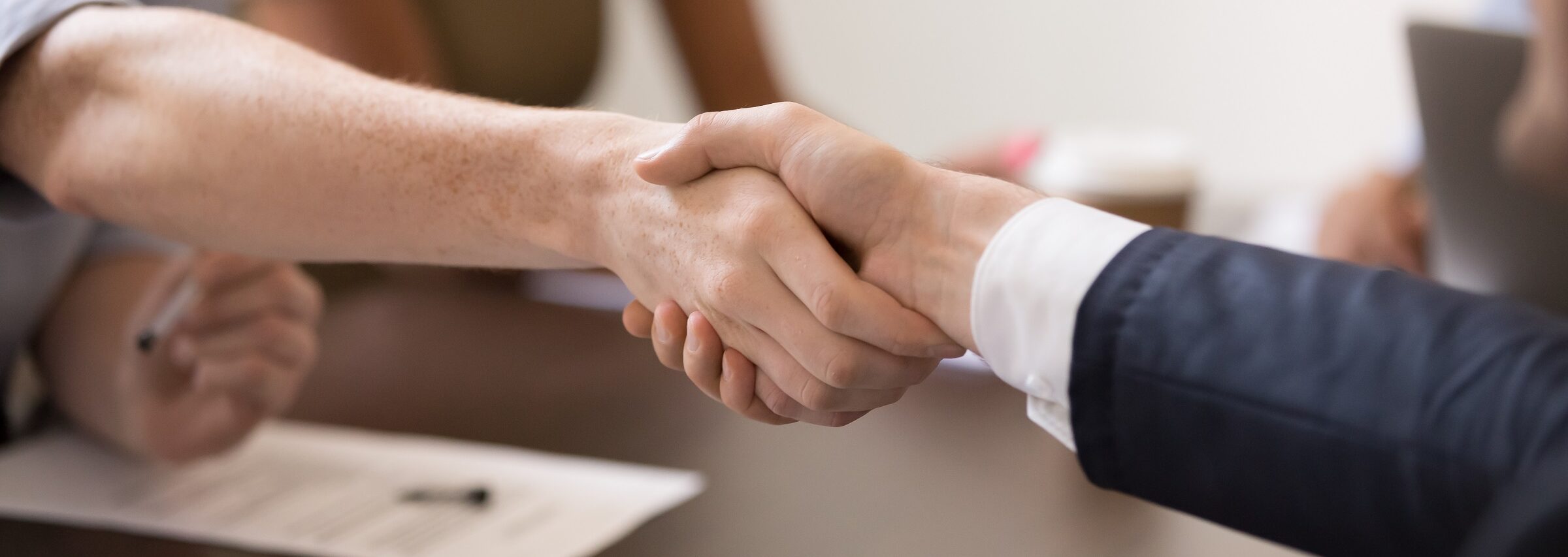 Negotiation Skills Training. Two people agree to deal by shaking hands after a successful negotiation.